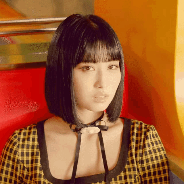 a woman with short black hair is wearing a yellow and black plaid top