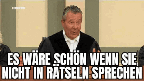 a man in a judge 's robe is giving a speech in a courtroom with a caption in german .
