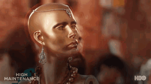 a mannequin with a shaved head is wearing a necklace and earrings and a headpiece .
