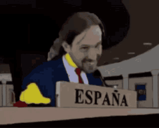 a man in a suit and tie is giving a thumbs up in front of a sign that says espana