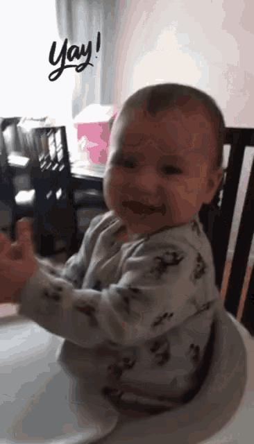 a baby is sitting in a high chair with the word yay written on the bottom