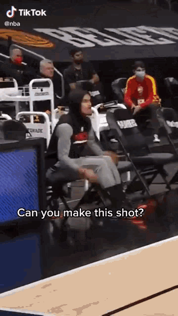 a basketball player is sitting in the stands during a game and talking to someone .