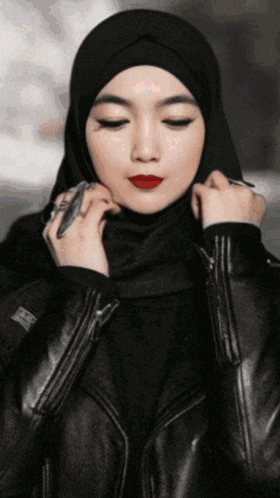 a woman wearing a black hijab and black leather jacket