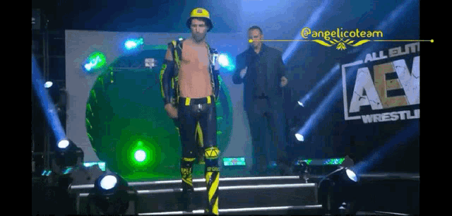 a man in a yellow and black outfit is walking on a stage in front of a sign that says aew wrestling