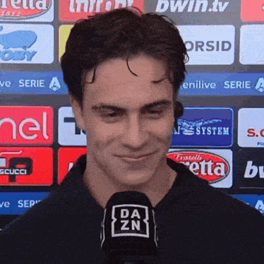 a man wearing a black shirt with a da zn logo on it