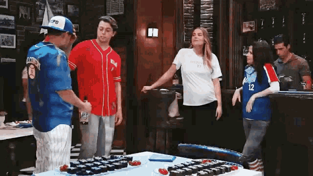 a group of people standing around a table with a cake on it .