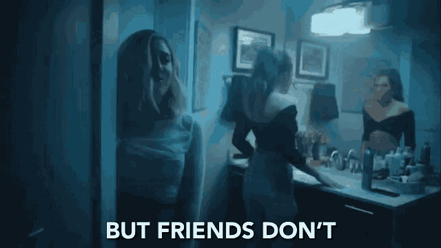 a woman is standing in front of a mirror in a bathroom talking to another woman .