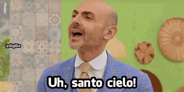 a bald man in a blue suit and tie says uh santo cielo