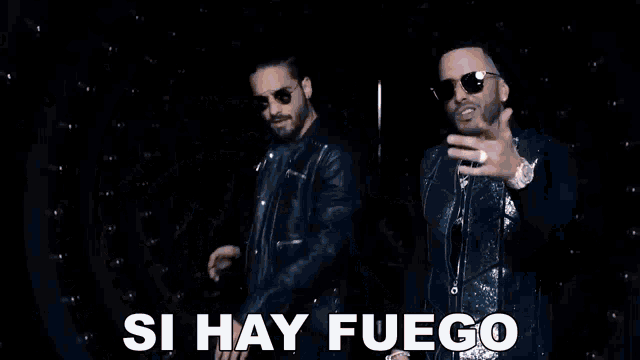 two men are dancing in front of a circle of lights and the words hay que apagarlo are visible