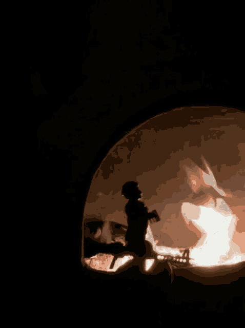 a silhouette of a person standing in front of a fire in a dark room .
