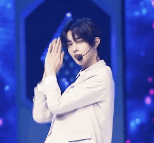 a young man wearing a white jacket and a microphone on his neck