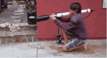 a young boy is kneeling down holding a water gun in front of a red wall