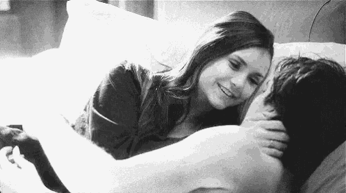 a woman is laying on top of a man in a bed .