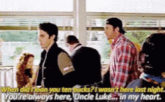 a man in a plaid shirt is talking to another man in a room .