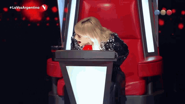 a woman sits at a podium with the words la voz argentina on the bottom