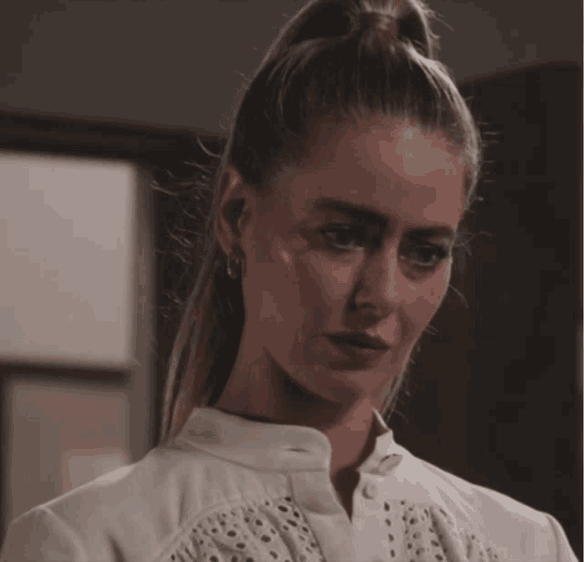 a close up of a woman 's face with a ponytail and earrings