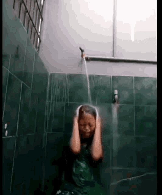 a young girl is taking a shower in a bathroom with a hose coming out of the faucet .