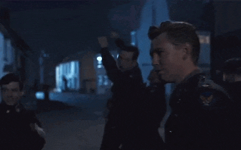 a group of men are standing on a dark street at night .
