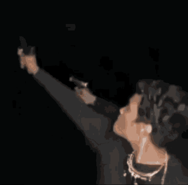 a blurry picture of a woman dancing in a dark room with her arms in the air .
