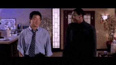 two men are standing next to each other in a room and one of them is wearing a blue shirt and tie