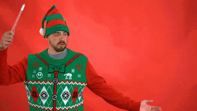 a man wearing an elf hat and an ugly christmas sweater says happy holidays on a red background