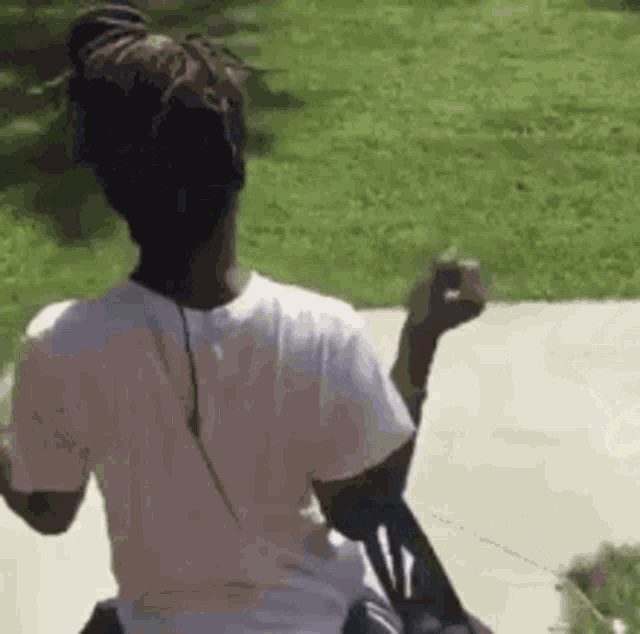 a woman in a white t-shirt is sitting on a bench in the grass .