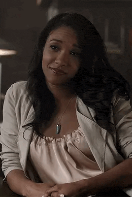 a woman is sitting at a desk wearing a white cardigan and a necklace .