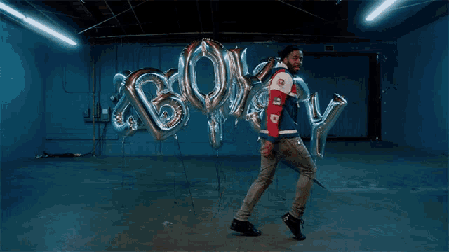 a man in a red white and blue jacket stands in front of a bunch of balloons with the word bully on them