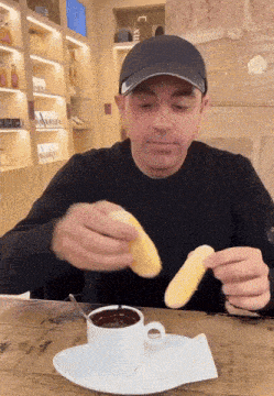 a man sitting at a table with a cup of coffee and a plate of food