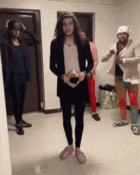 a man with long hair is holding a tambourine in a room