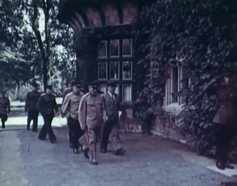 a black and white photo of a group of men walking down a sidewalk