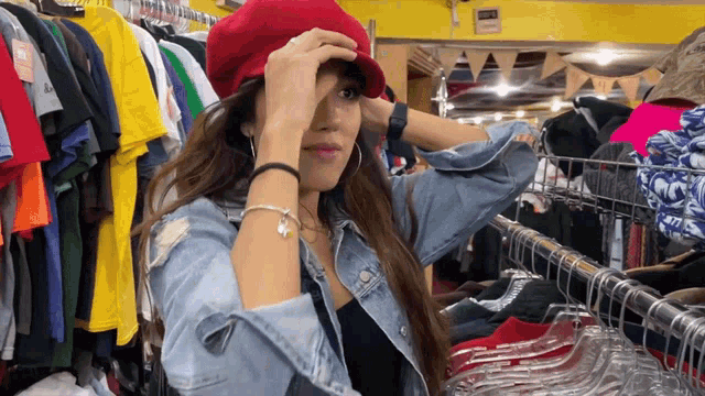 a woman wearing a red hat stands in front of clothes racks