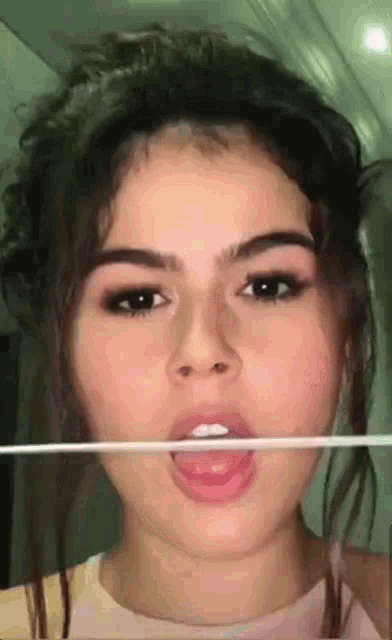 a close up of a woman 's face with a toothpick in her mouth