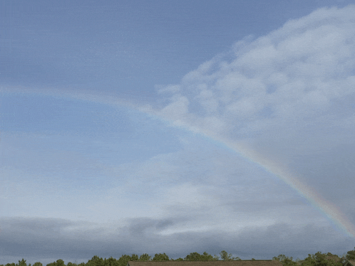a rainbow is visible in a cloudy sky over a house