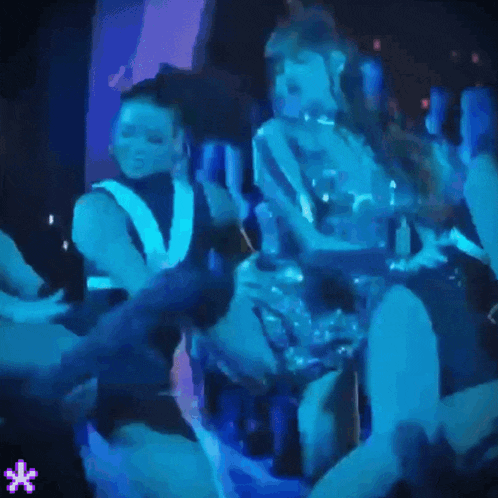 a group of people dancing in a dark room with a blue light behind them