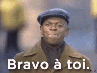 a man wearing a hat and a brown coat is saying bravo a toi .