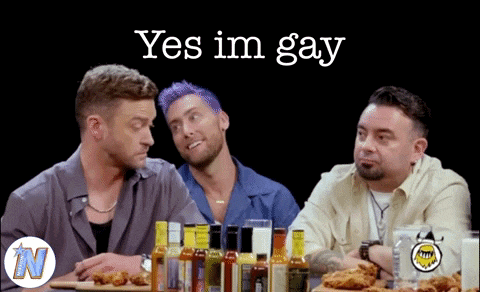 three men are sitting at a table with bottles of hot sauce and the words yes im gay