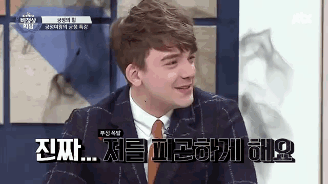 a man in a suit and tie is smiling and talking in a foreign language .