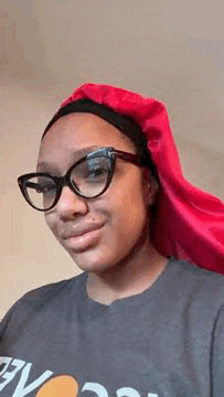 a young woman wearing glasses and a red hat is smiling .