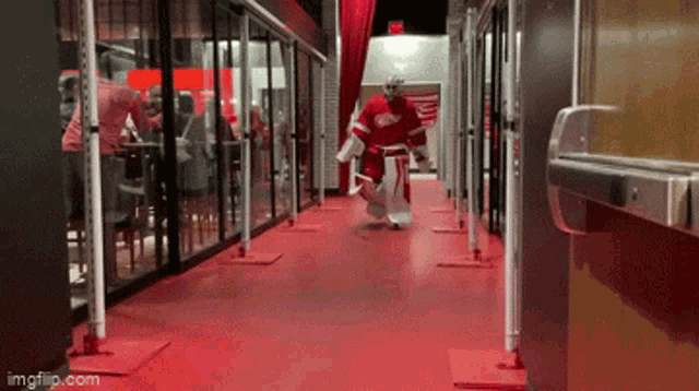 a hockey goalie is walking down a hallway with a red carpet