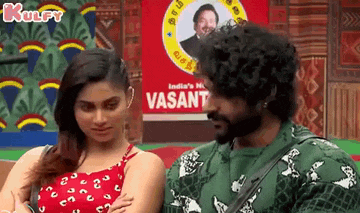 a man and a woman are standing next to each other in front of a sign that says ' vasant ' on it .