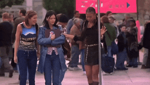 three women walking in front of a sign that says hollywood