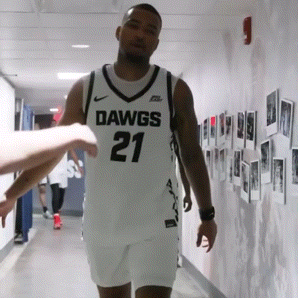 a man in a dawgs 21 jersey walks in a hallway