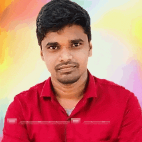 a man in a red shirt looks at the camera with a colorful background behind him