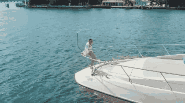 a woman in a white dress is standing on the side of a boat