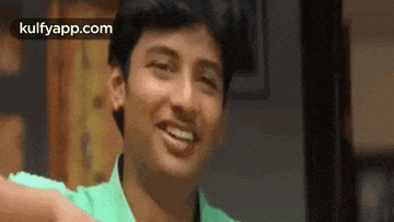 a young man in a green shirt is smiling and laughing .