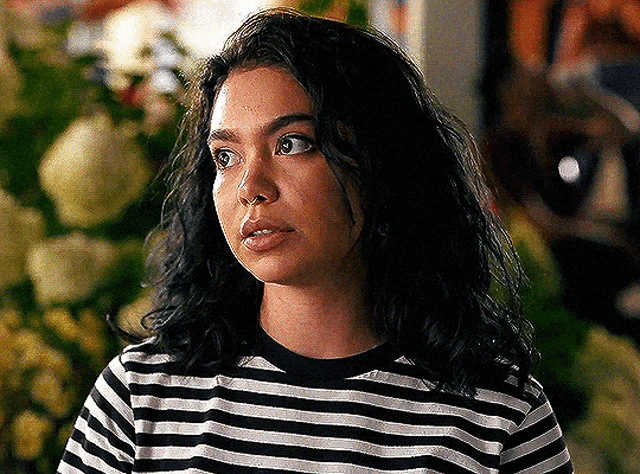 a woman is wearing a black and white striped shirt and looking at the camera .