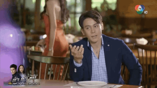 a man in a suit sits at a table with a plate of food in front of a sign that says isu