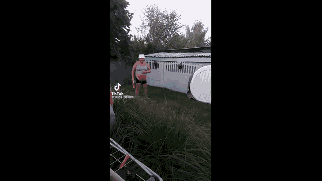 a man is sitting in a hot tub outside of a house .