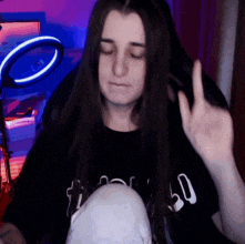 a woman with long hair is giving the middle finger while wearing a black shirt with the number 50 on it .